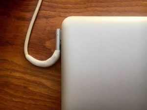 Cable del cargador de Macbook Pro reparado con kintsuglue, enchufado al Macbook